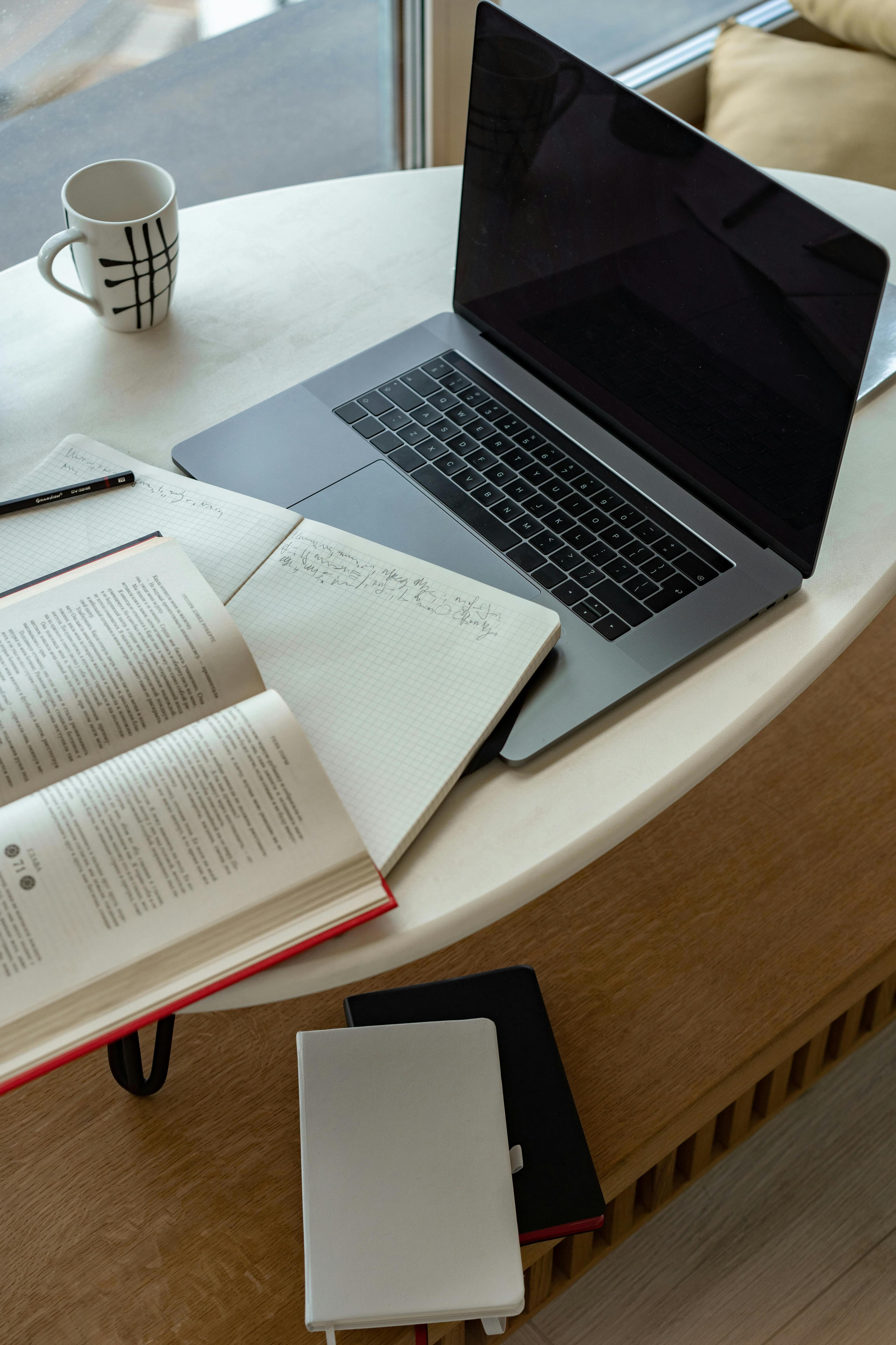 A laptop, open book and notebook on a desk, online learning at BRS Online School