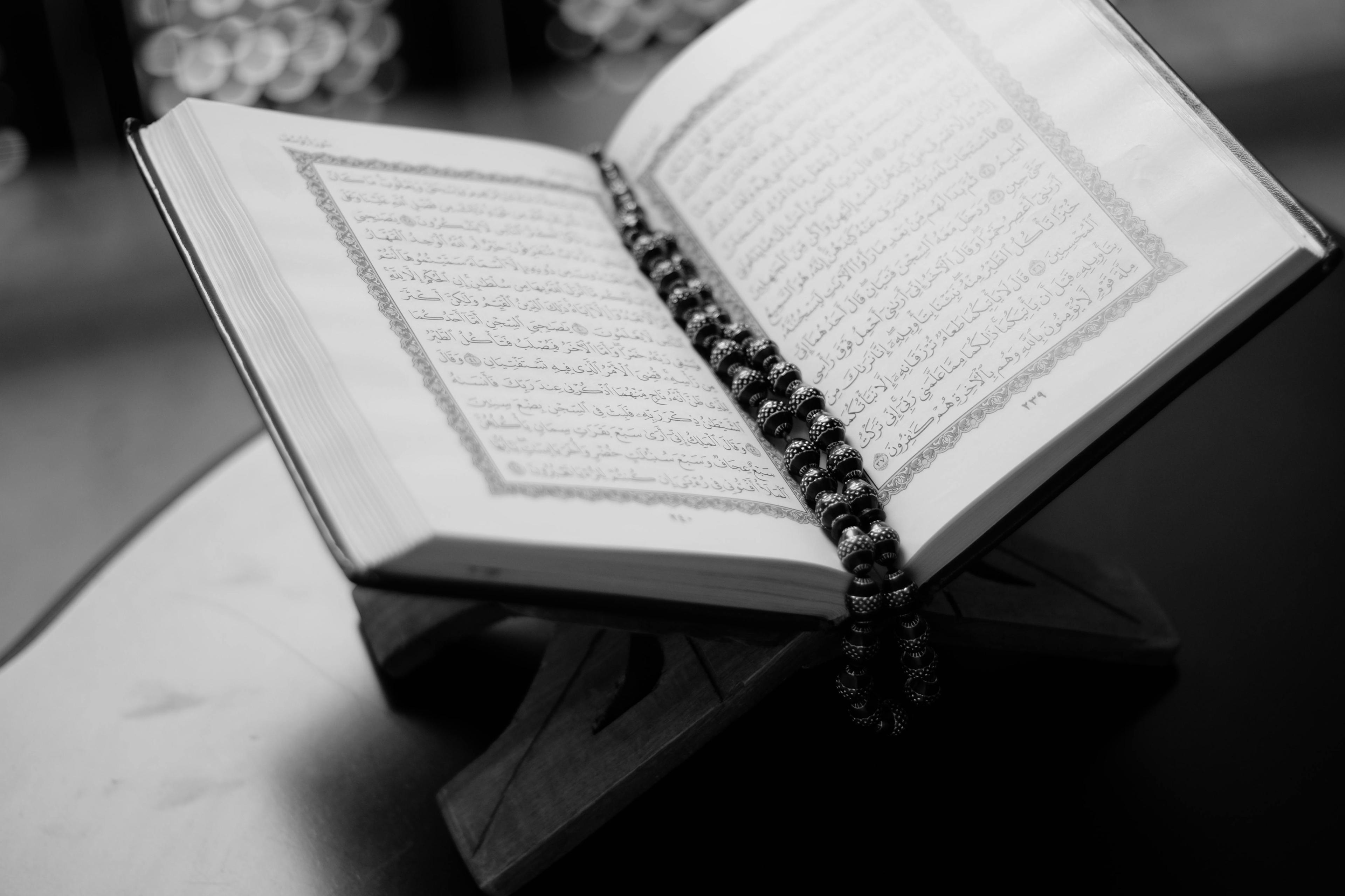 An open Quran with prayer beads resting on a wooden stand